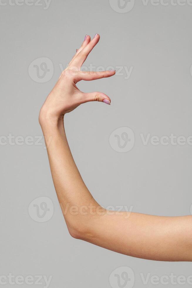 Female hand sign against gray background in studio photo