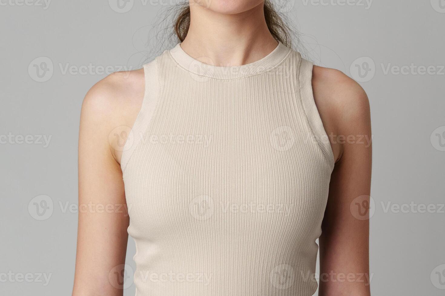 Female body in beige top on gray background photo