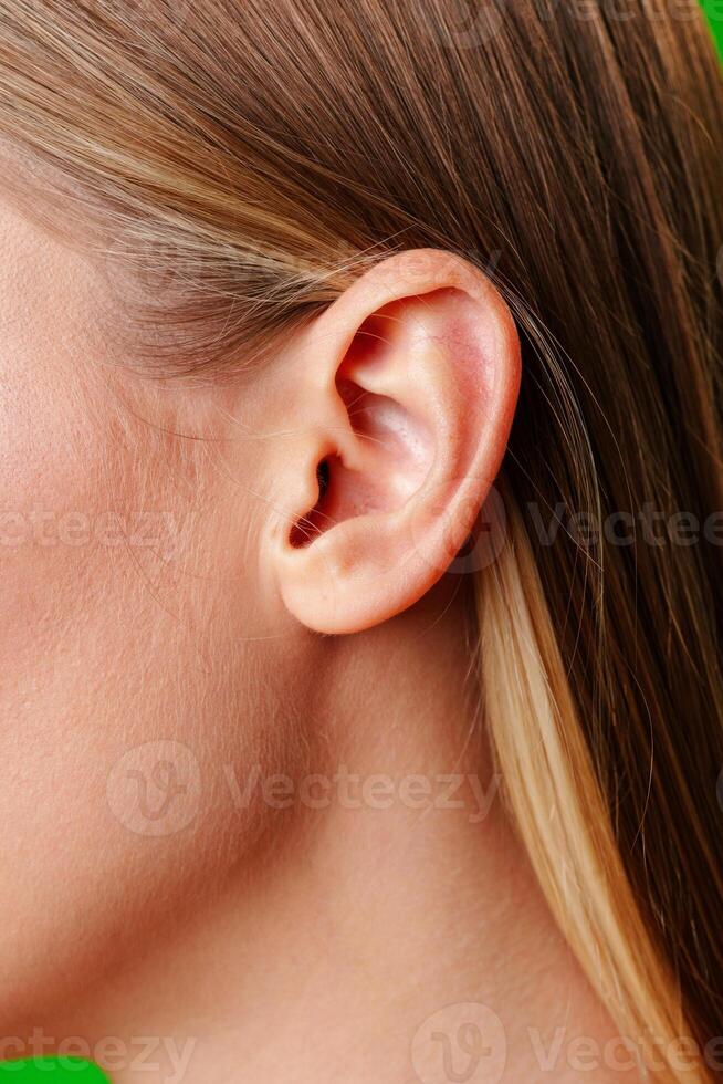 Womans Ear Close Up With Green Background photo