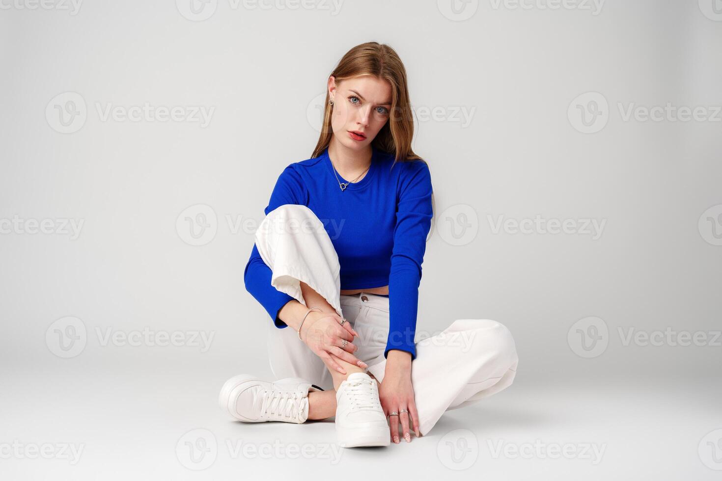 Young Woman model in Blue Top and White Pants posing on white background photo