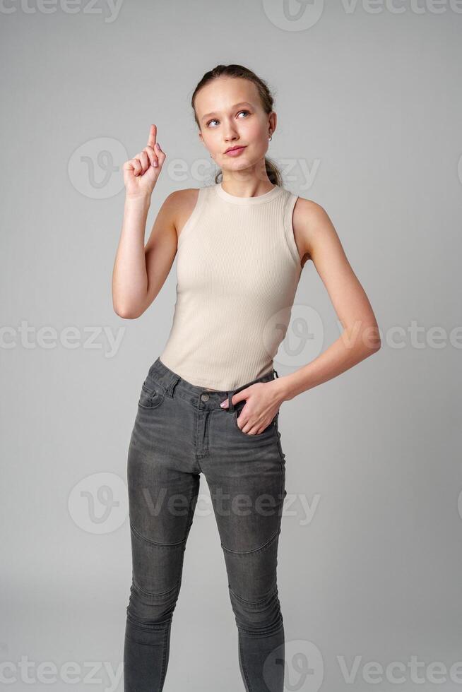 Young Woman Gesturing With One Finger Up Against a Grey Backdrop photo