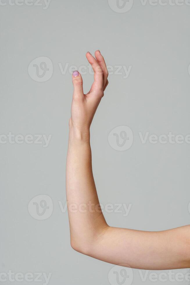 Female hand sign against gray background in studio photo
