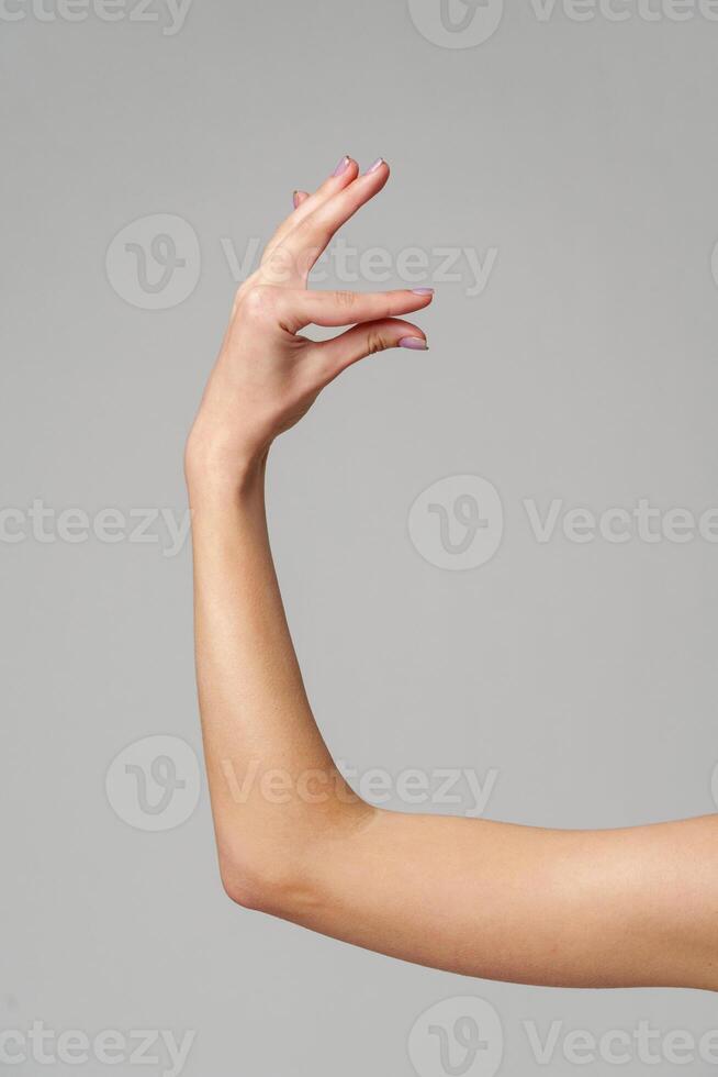 Female hand sign against gray background in studio photo