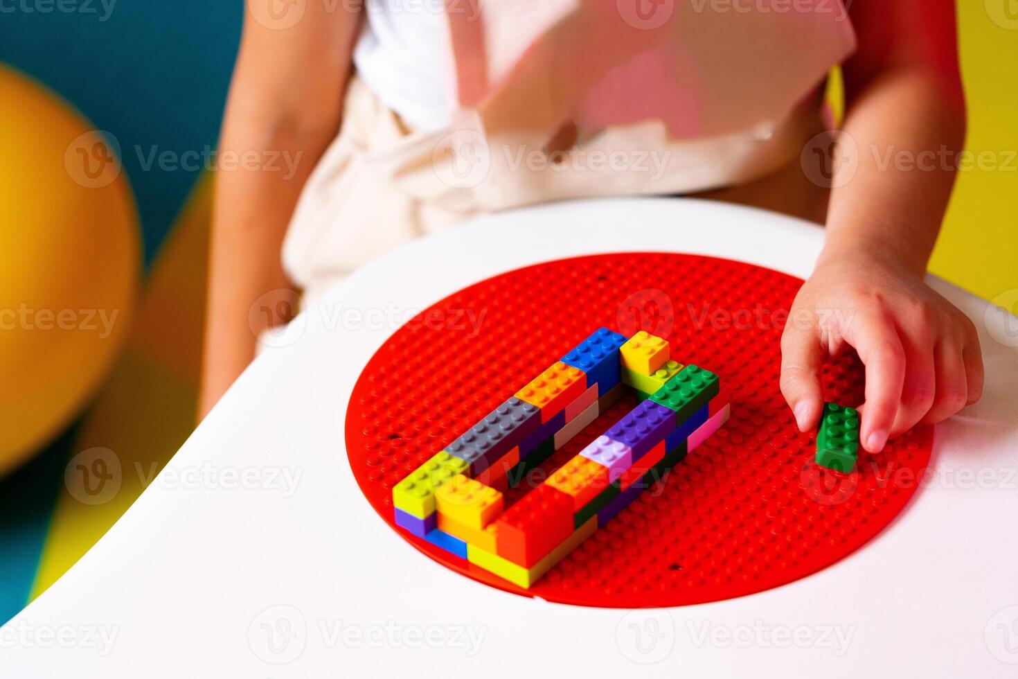 Child Engaged in Creative Play With Colorful Building Blocks on a Round Base photo