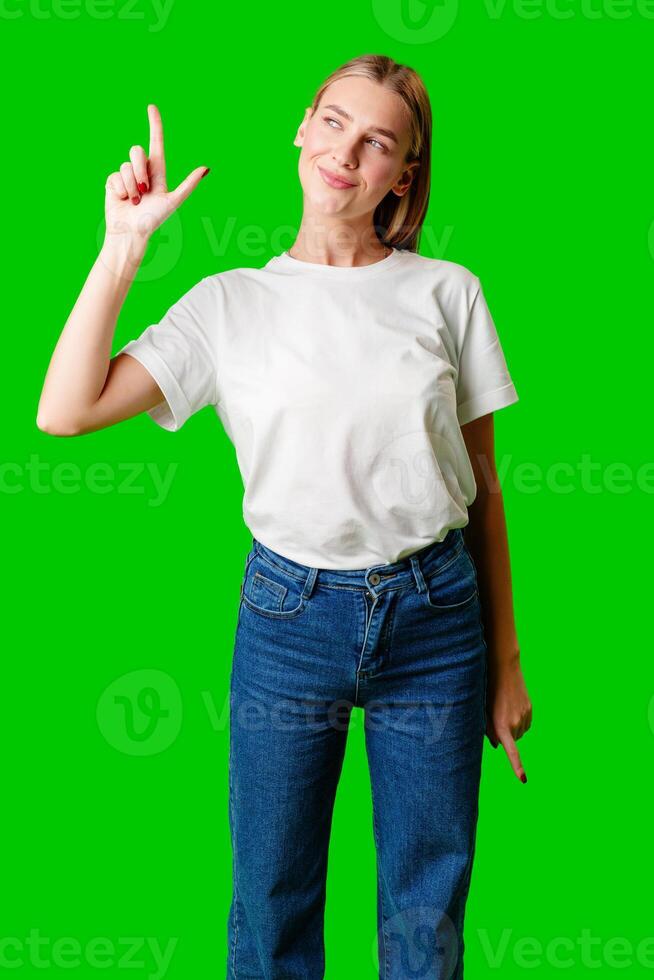 Young Woman Pointing Up Against Green Background photo