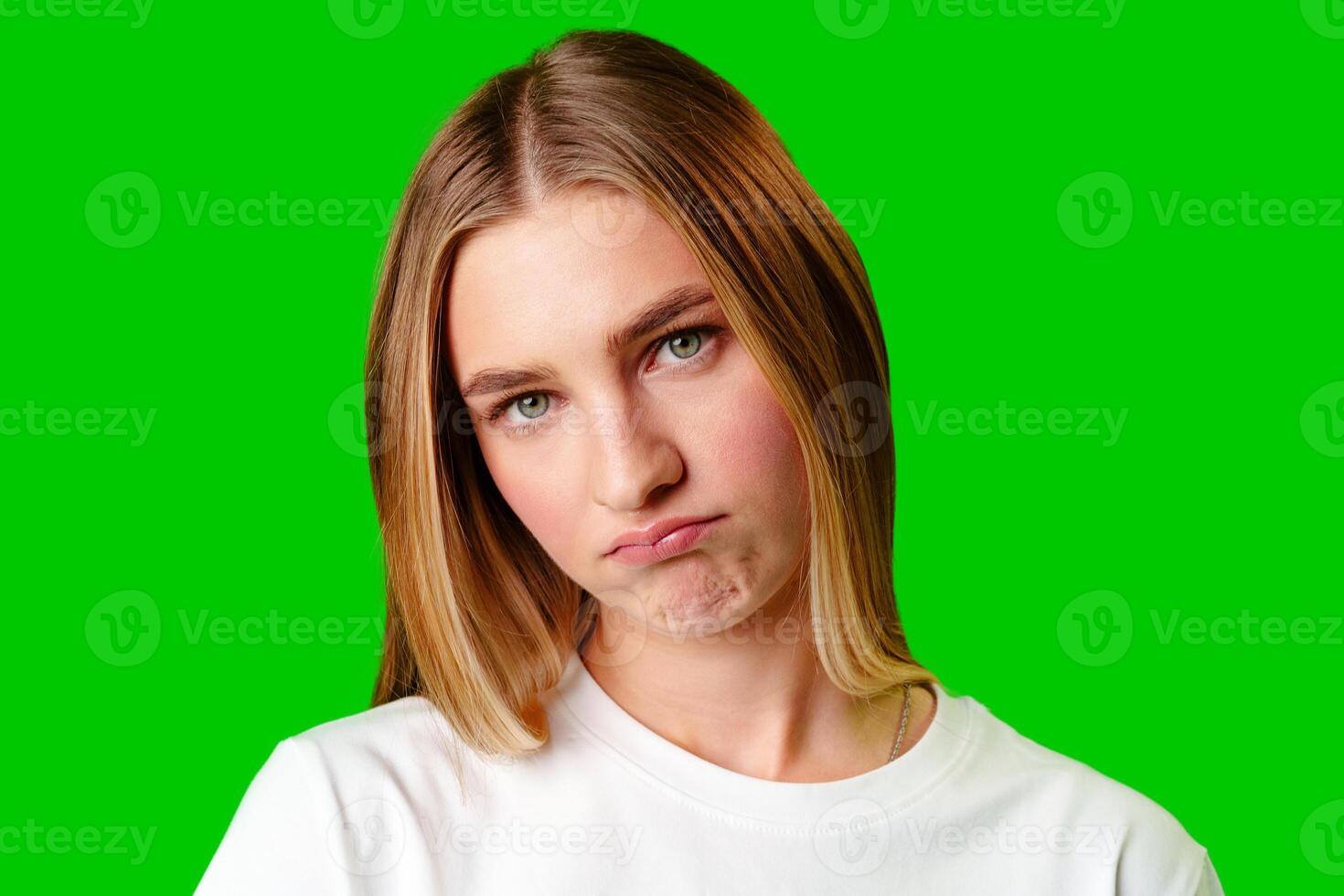 Young Woman With Pursed Lips Expressing Skepticism Against Green Screen Background photo