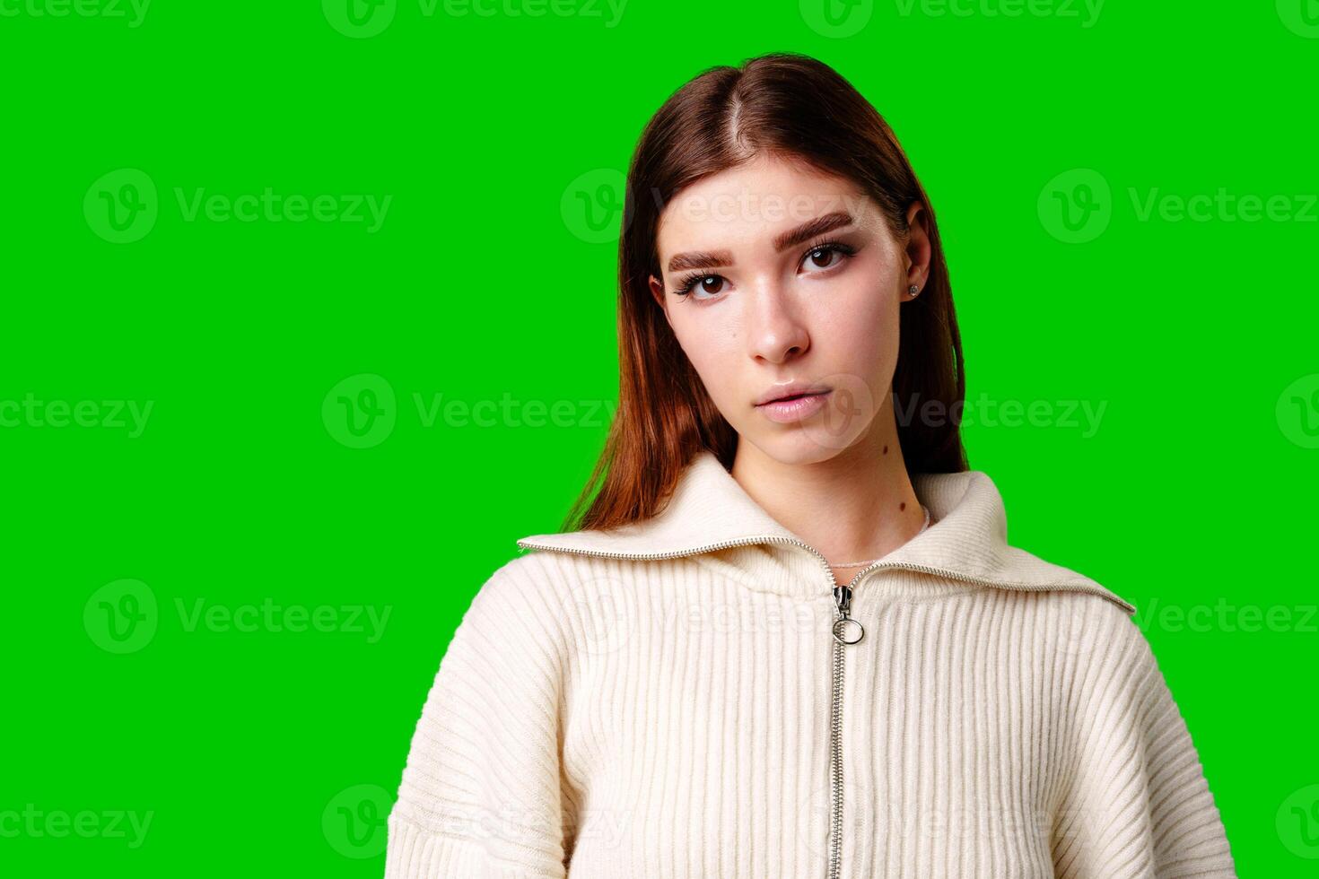 A woman wearing a white sweater and a gray skirt stands in a casual pose, showcasing her stylish outfit. photo