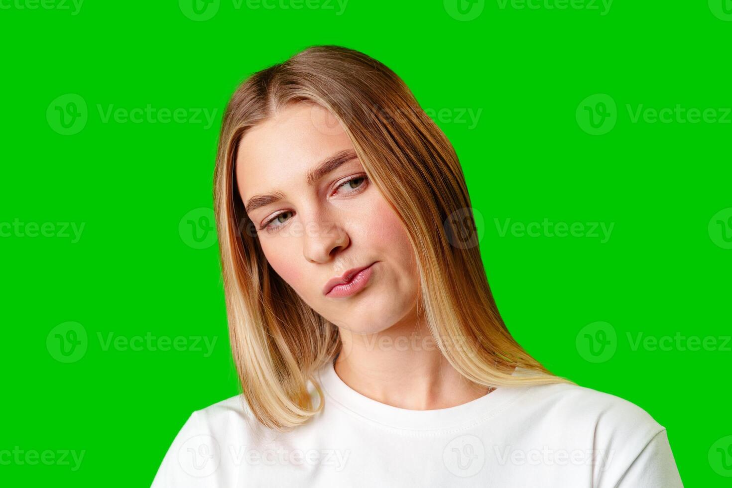 Young Woman With Pursed Lips Expressing Skepticism Against Green Screen Background photo