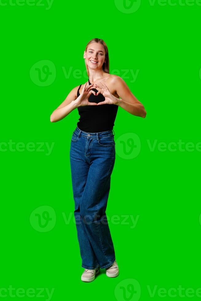 Young Woman Making Heart With Hands on green background photo