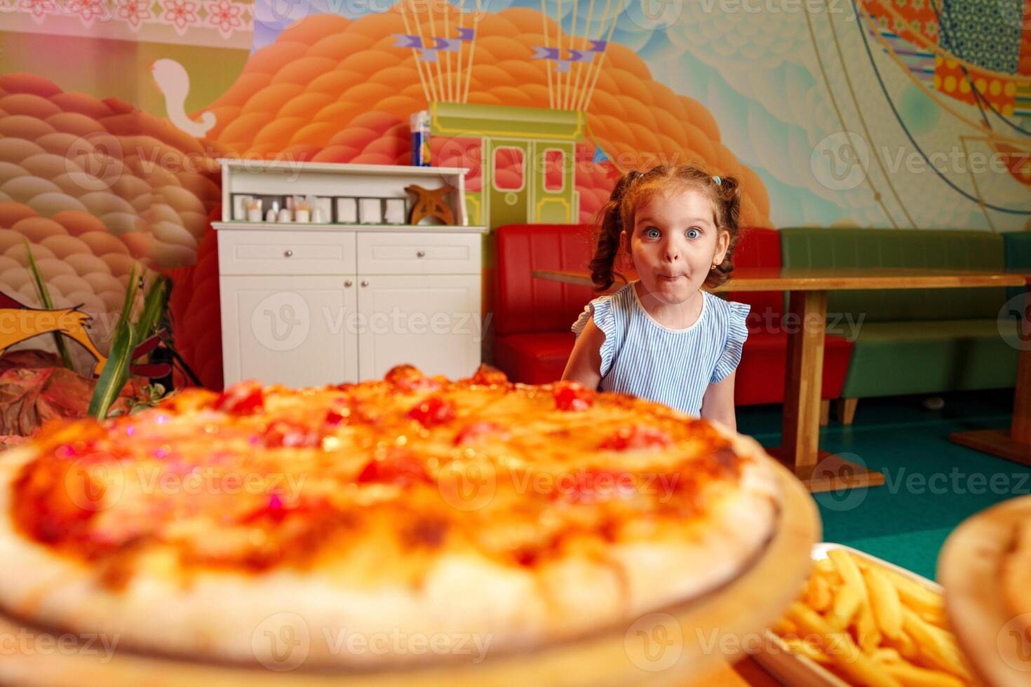 Little Girl Sitting in Front of Pizza photo