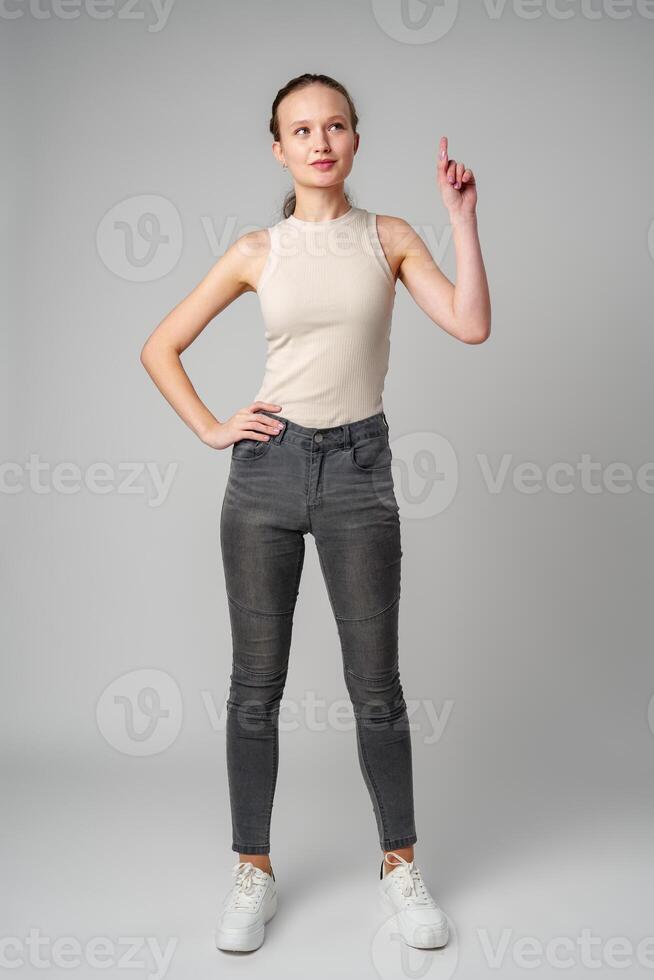 Young Woman Gesturing With One Finger Up Against a Grey Backdrop photo