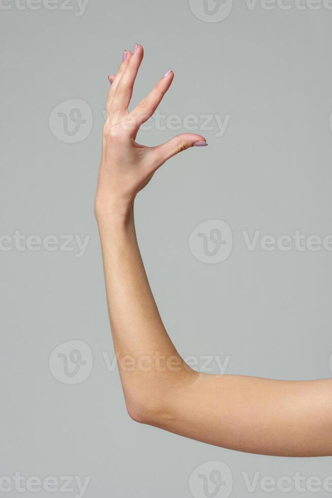 Female hand sign against gray background in studio photo