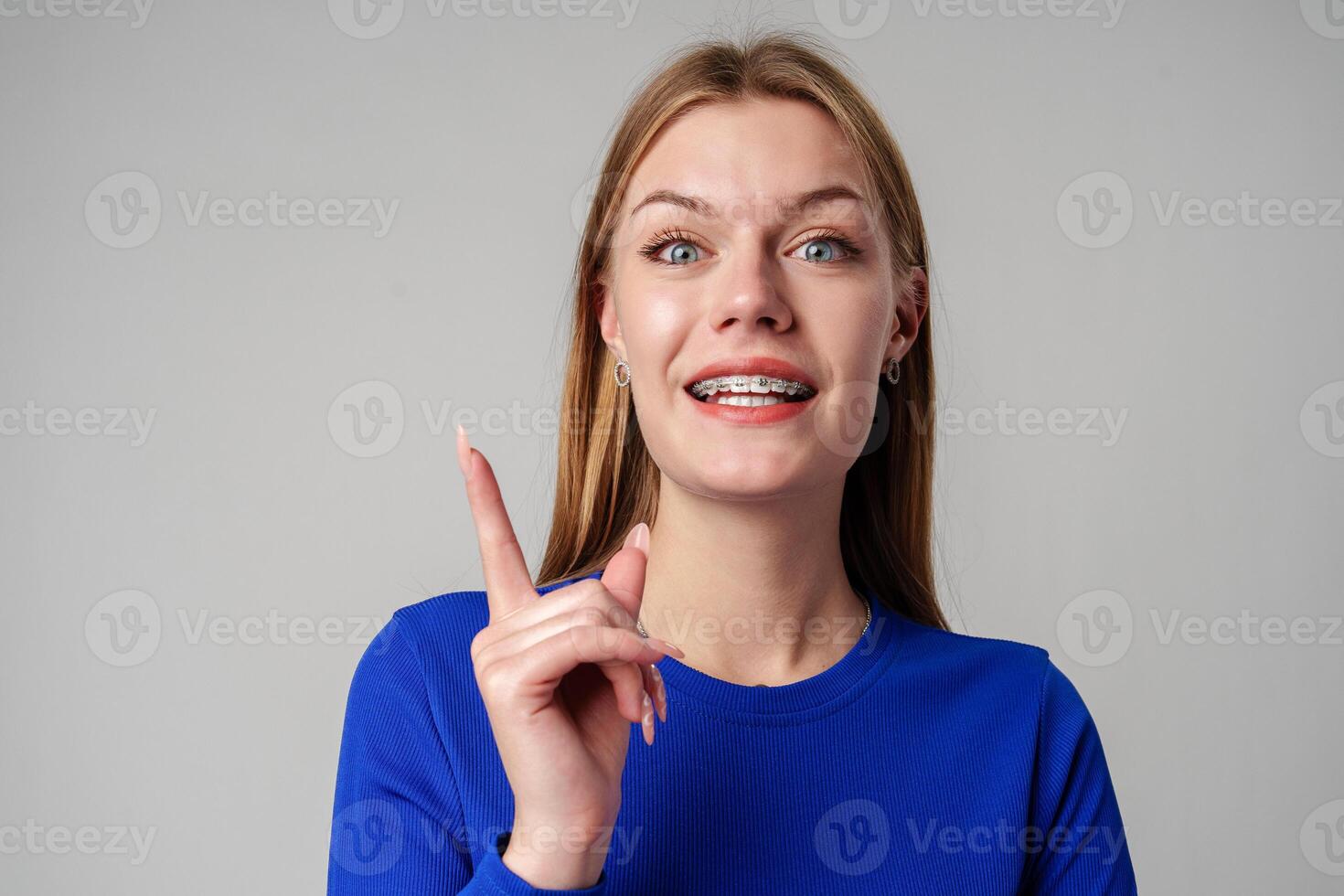 Young Woman Gesturing With Her Finger While Speaking Against a Gray Background photo