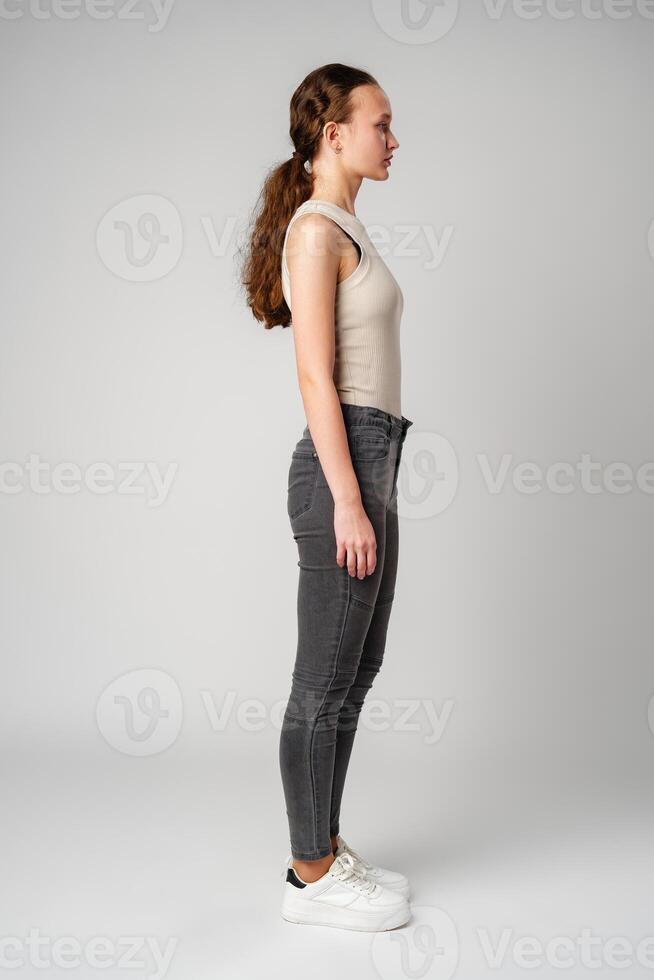 Profile portrait of a young woman with curly hair on gray background photo
