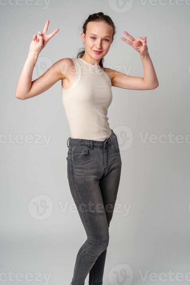 Young Girl Making a Peace Sign on gray background photo