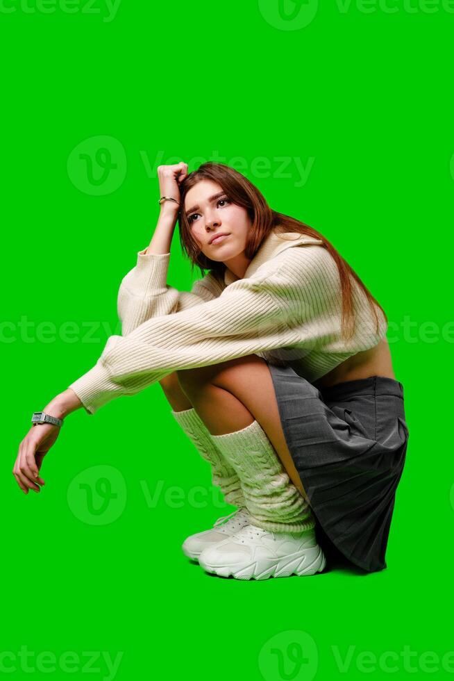 Woman Sitting on Ground in Front of Green Screen photo