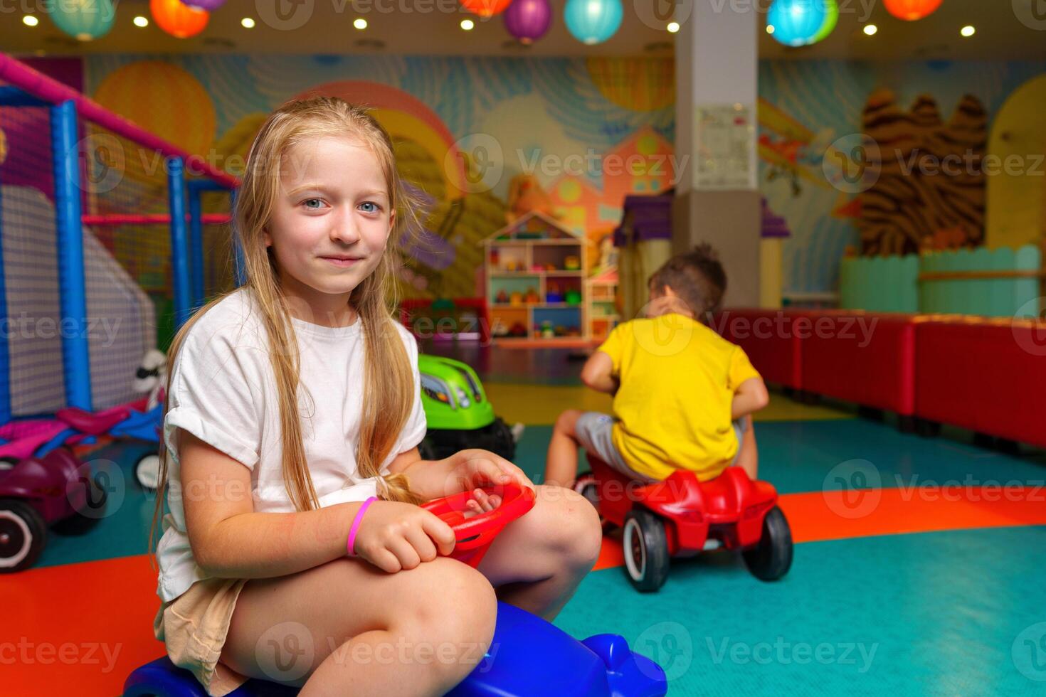 Young Girl Sitting on Toy Car in Play Room photo
