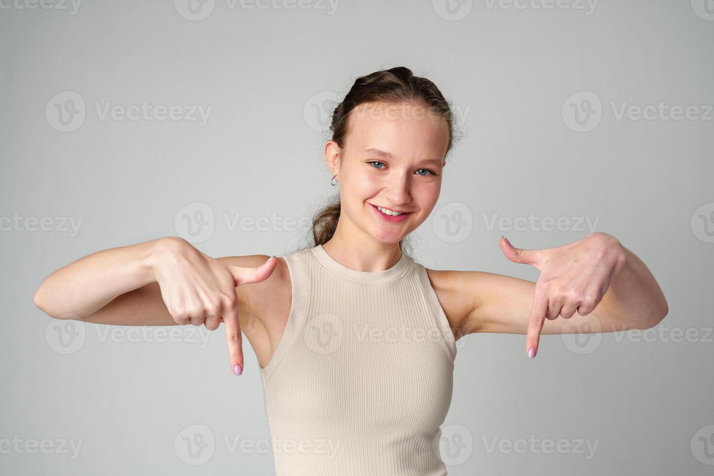 Young Woman in Tank Top Pointing Down in studio photo