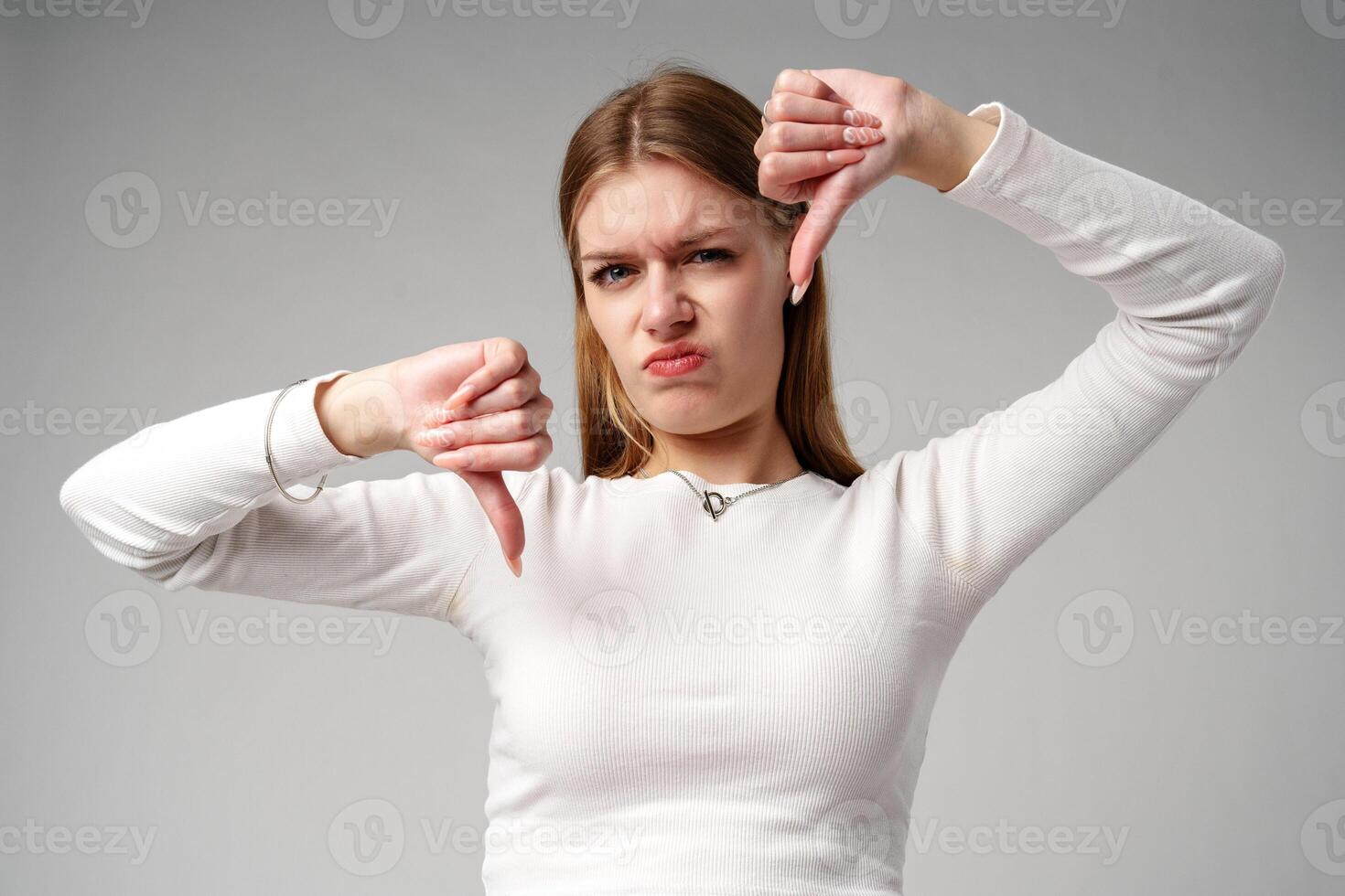 Young Woman Pointing Finger Down at Camera in studio photo