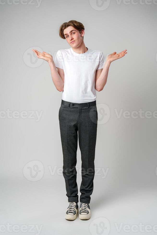 Young Man in Casual Attire Shrugging Shoulders Expressing Uncertainty in Studio photo