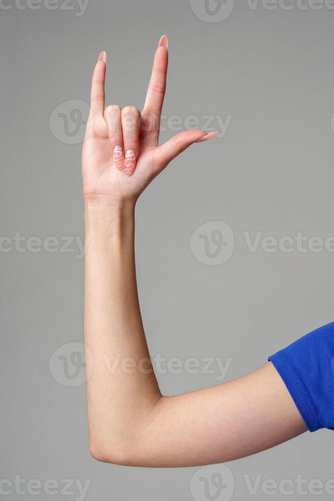 Female hand sign against gray background in studio photo