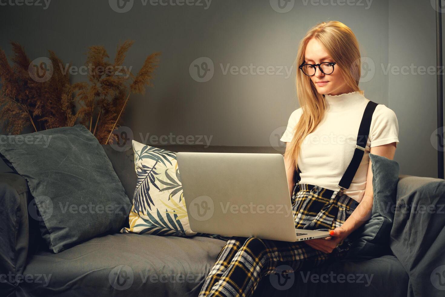 Young woman working on laptop at home, sitting on the sofa. Concept during coronavirus photo
