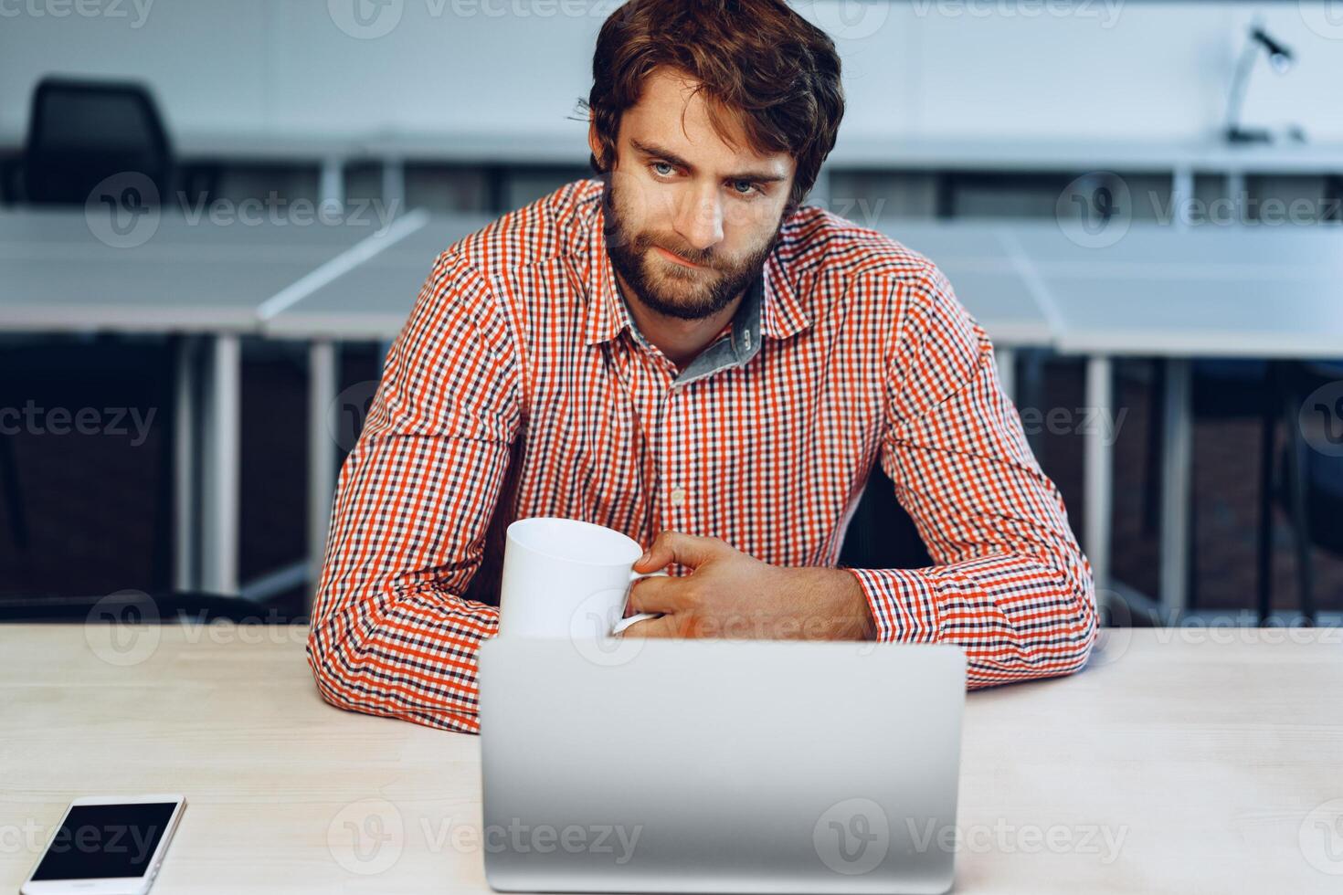 Puzzled thoughtful businessman sitting at his working table in an office photo