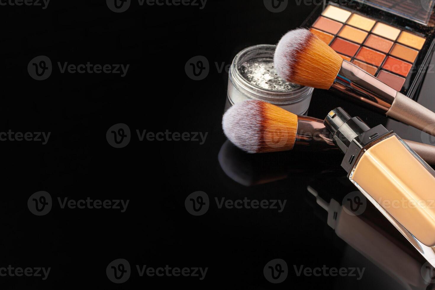 Professional makeup brushes and tools, make-up products set on dark table photo