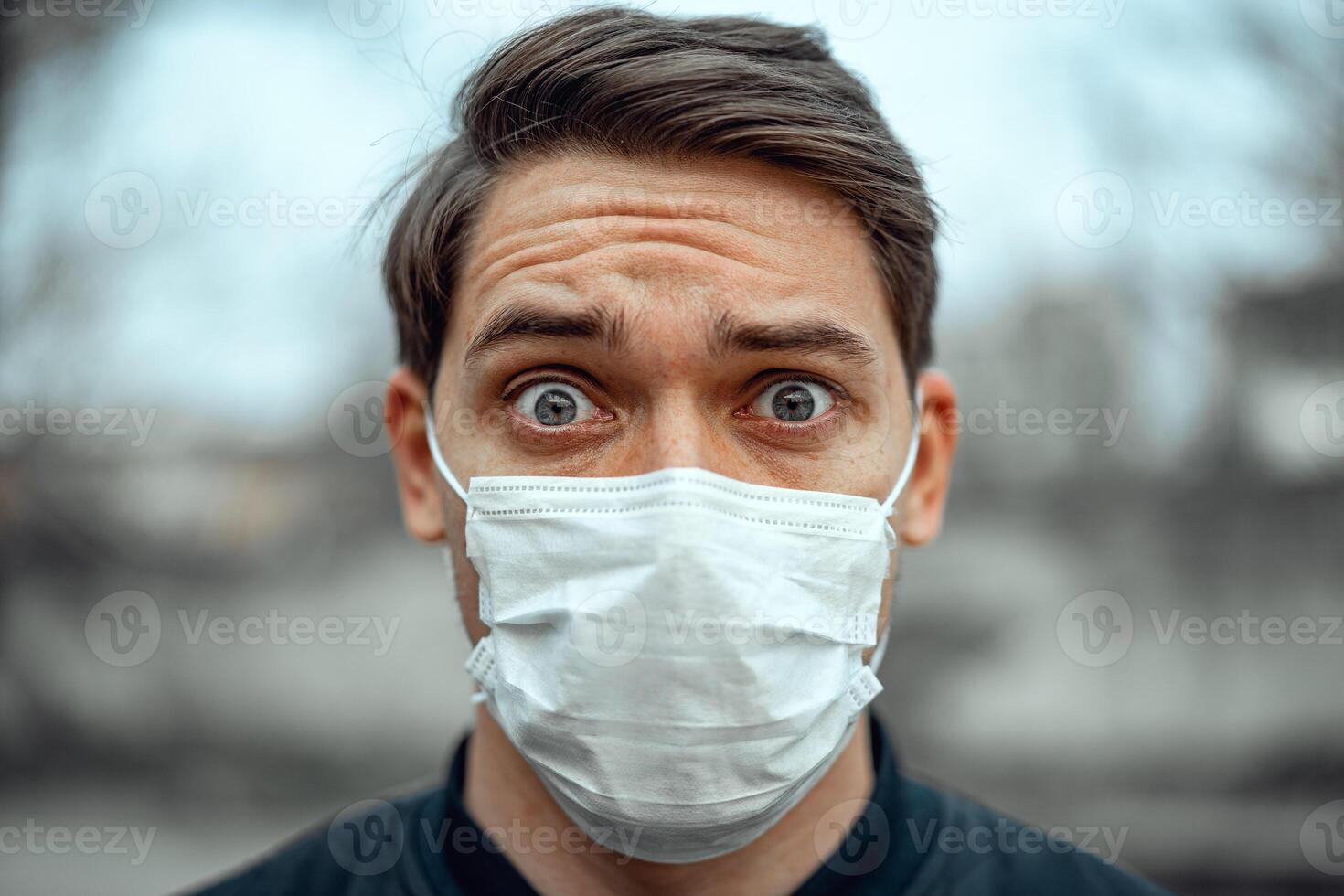 Portrait man in medical mask. Young man stands on light background and looking at camera. COVID-19 Pandemic Coronavirus. photo