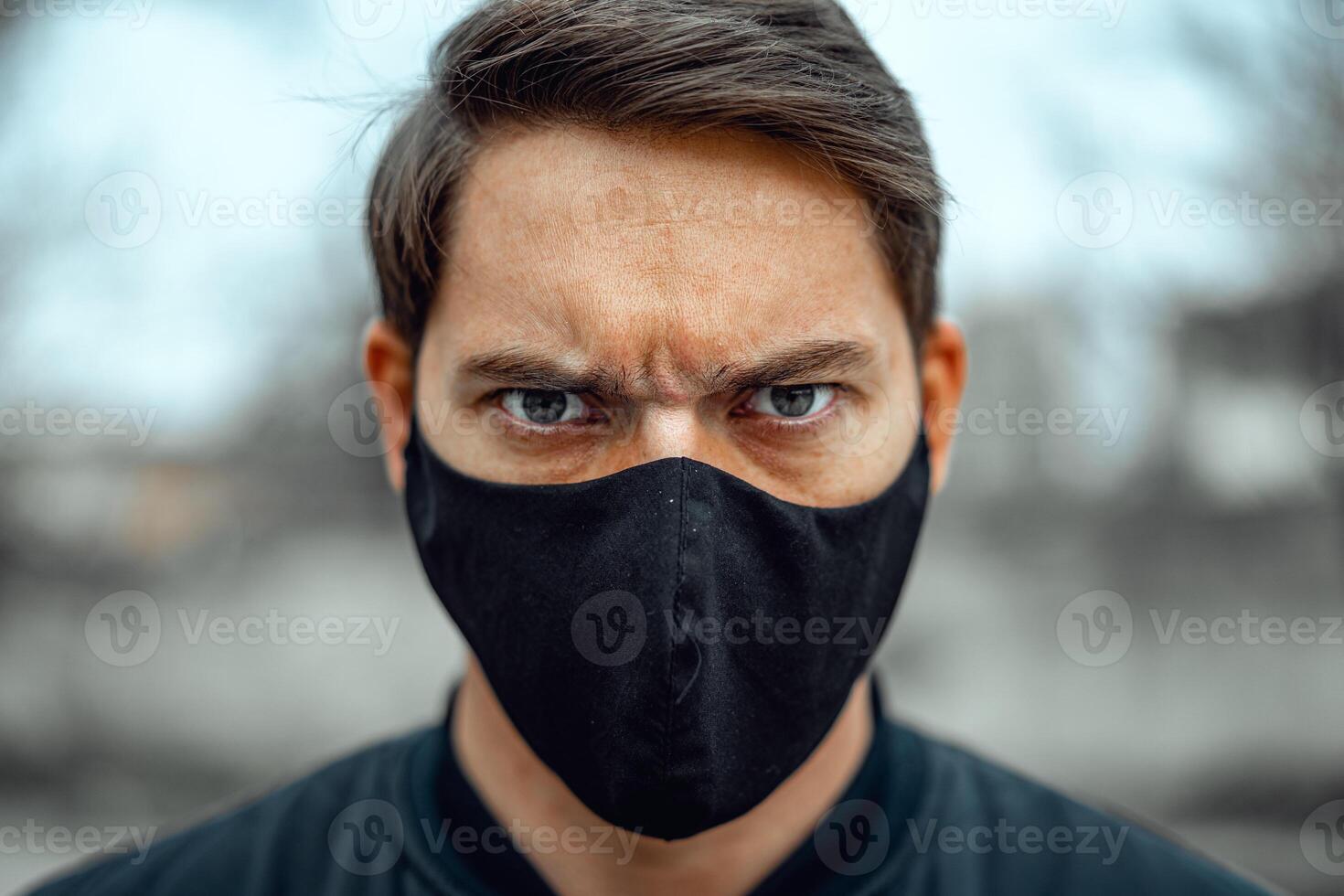 Portrait man in medical mask. Young man stands on light background and looking at camera. COVID-19 Pandemic Coronavirus. photo