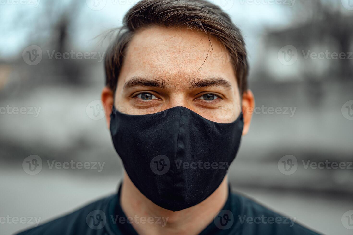 Portrait man in medical mask. Young man stands on light background and looking at camera. COVID-19 Pandemic Coronavirus. photo