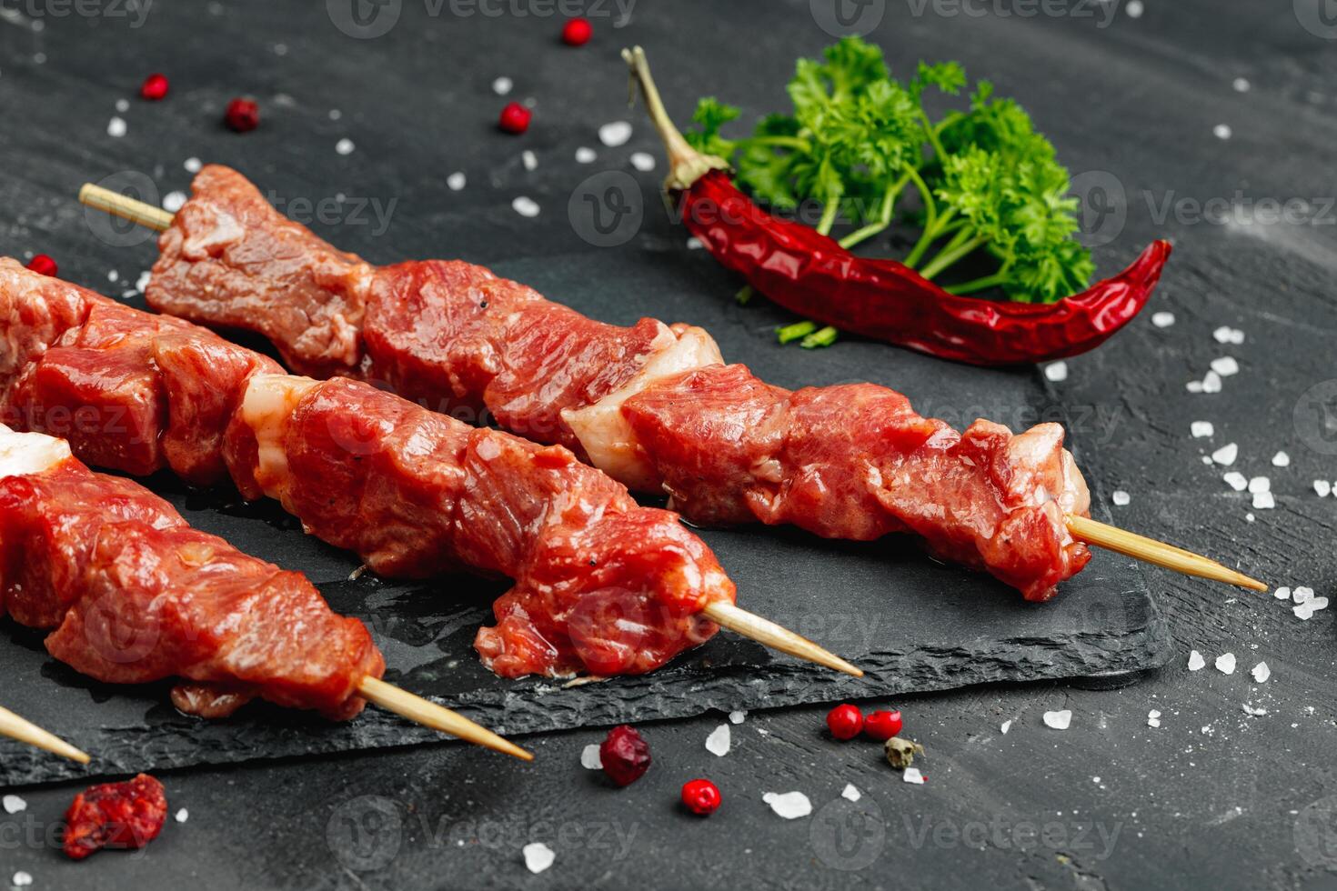 Raw beef kebab with herbs on a dark board photo