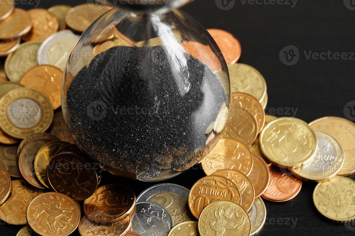 Time is money. Close up of hourglass with money coins photo