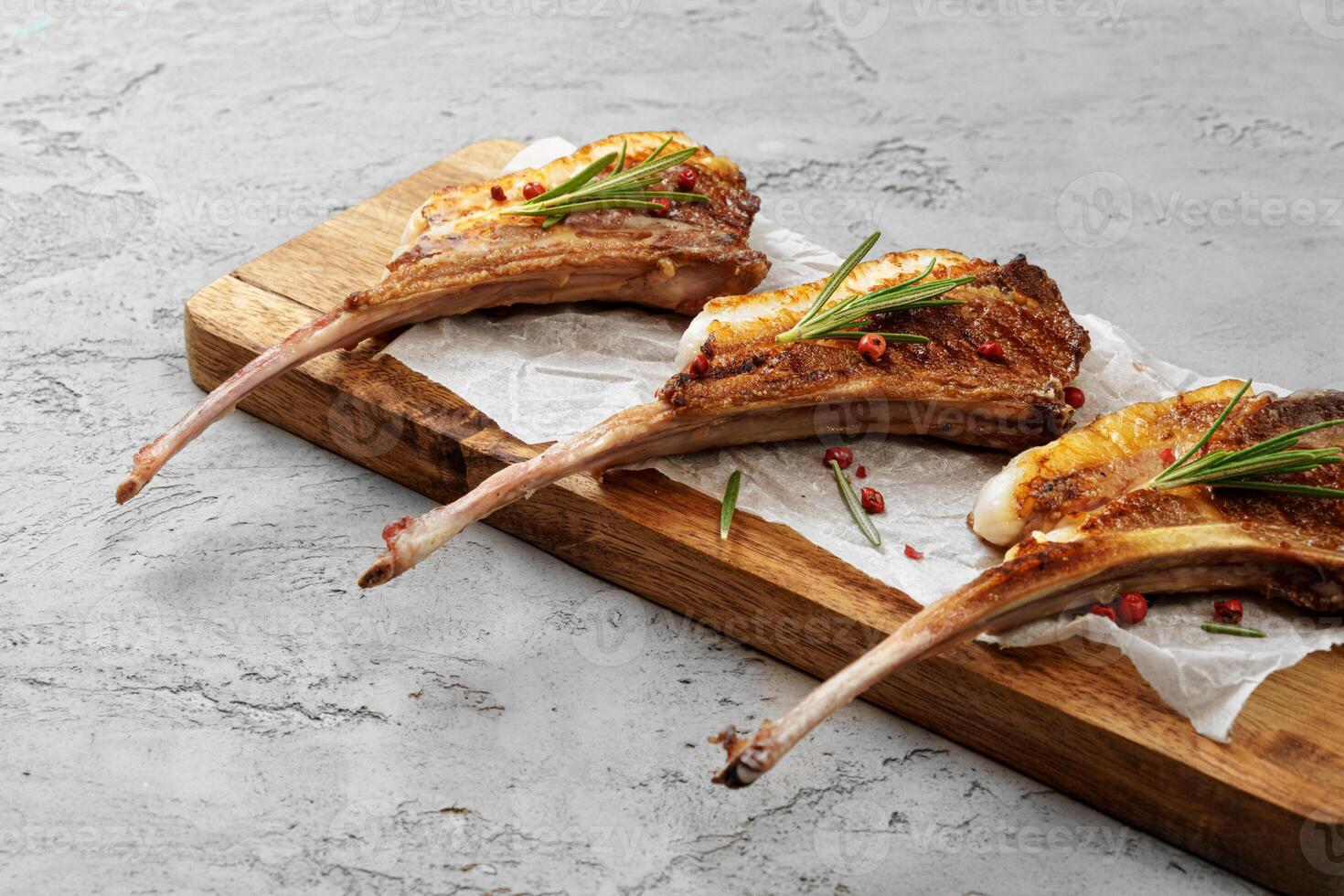 Grilled rack of lamb served on a wooden board photo