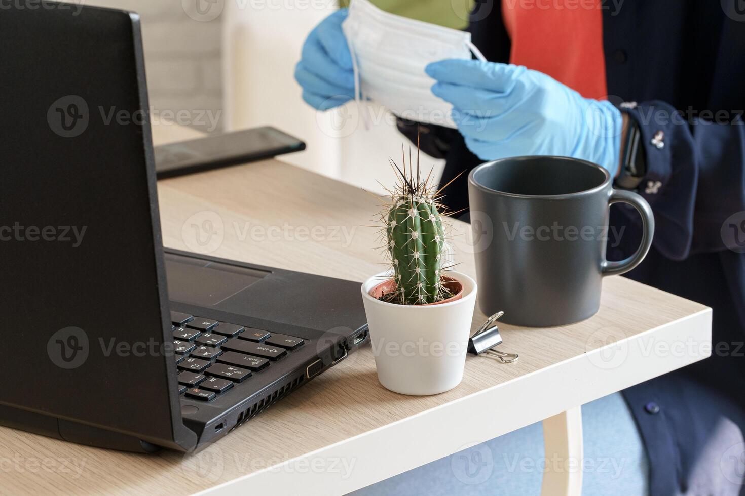 Female hands holding medical protective mask above working table photo