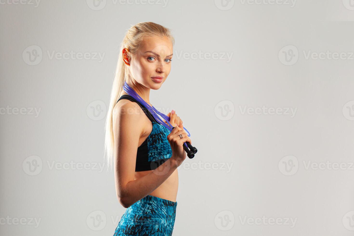 Fit blonde woman in sportswear holding jump rope photo