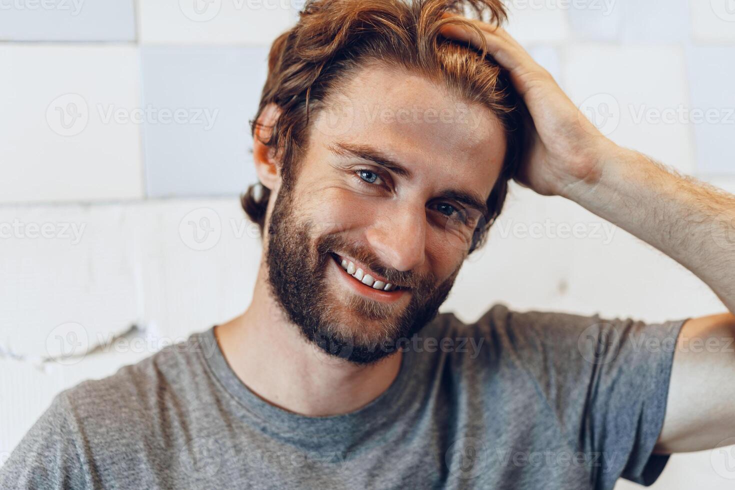 Portrait of a young bearded man standing against grunge weathered wall photo