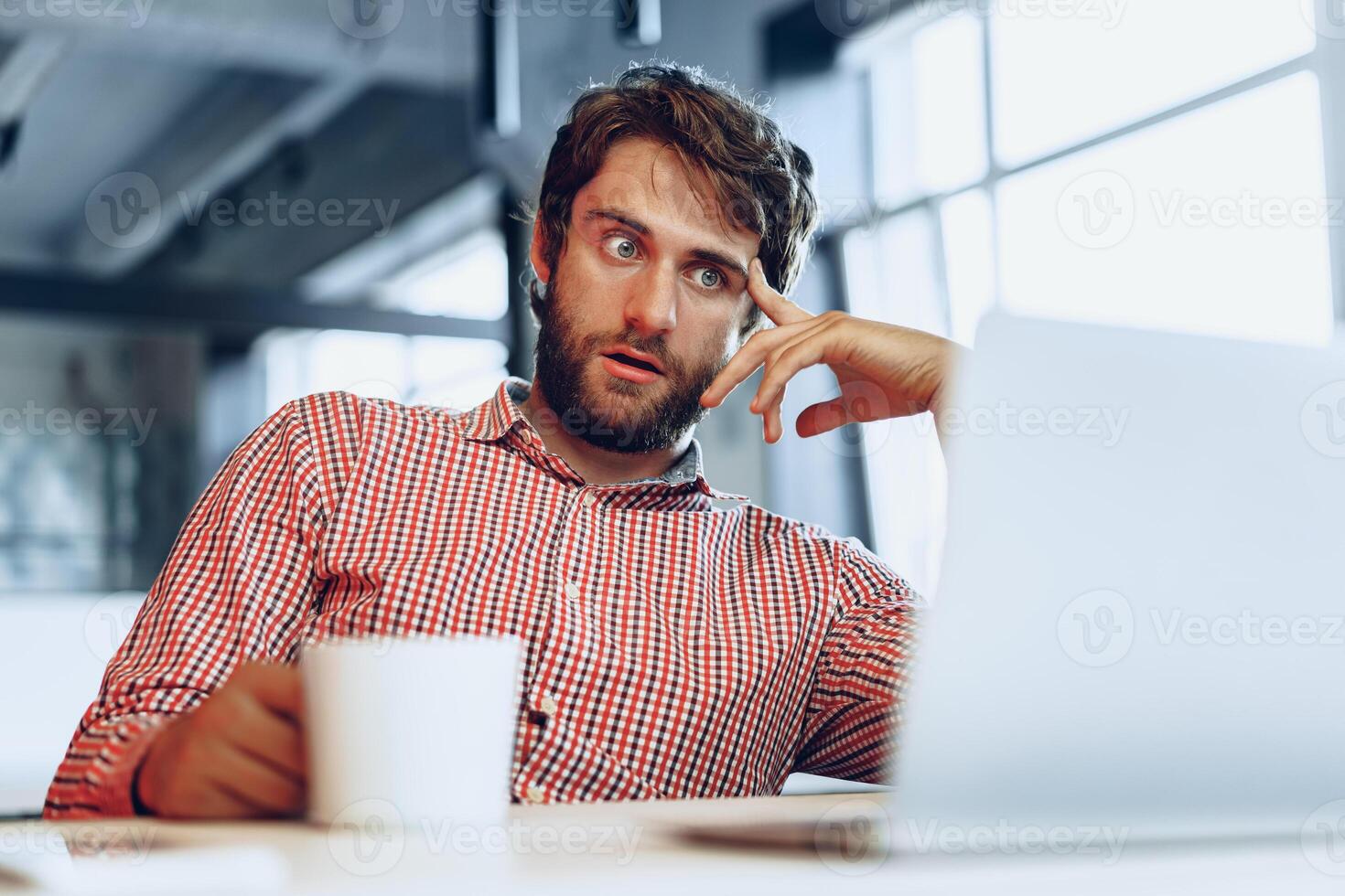 Puzzled thoughtful businessman sitting at his working table in an office photo