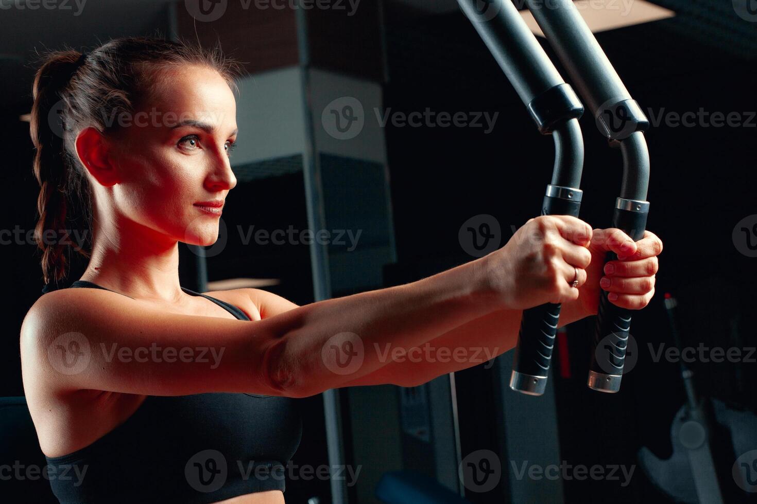 Young attractive woman doing exercises for arms in a training machine photo