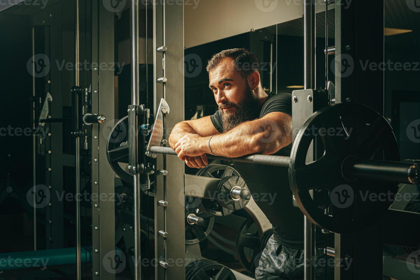 Fit man doing squats in a training machine photo