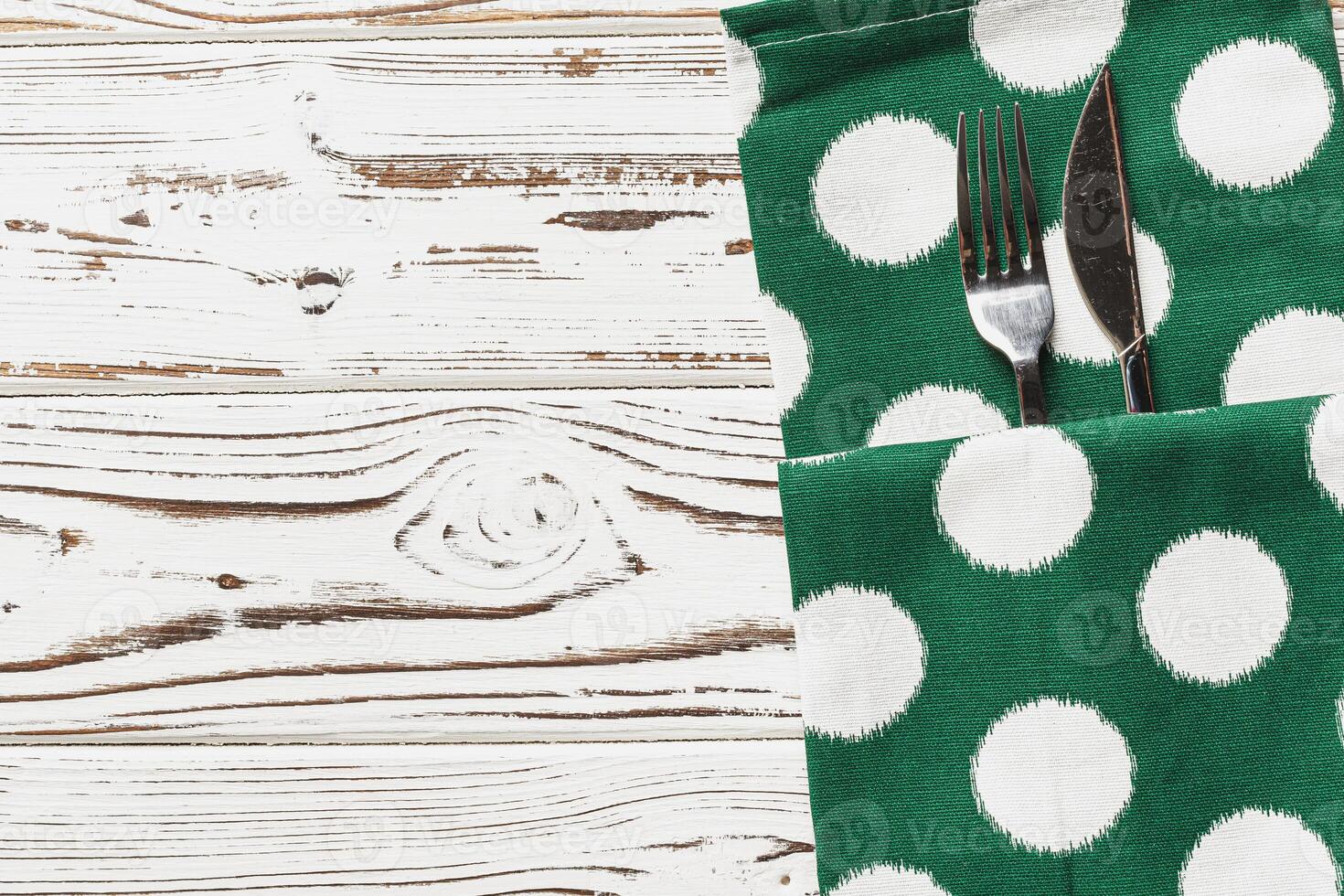 Green polka dot napkin on weathered wooden background photo