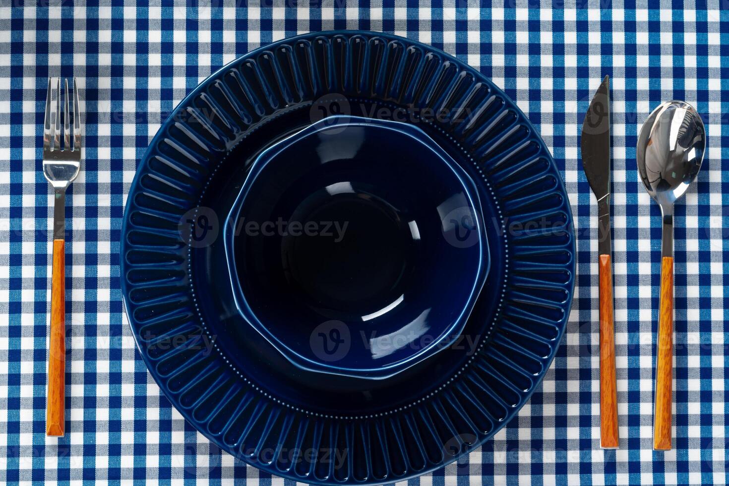 Deep blue ceramic plate with cutlery close up photo