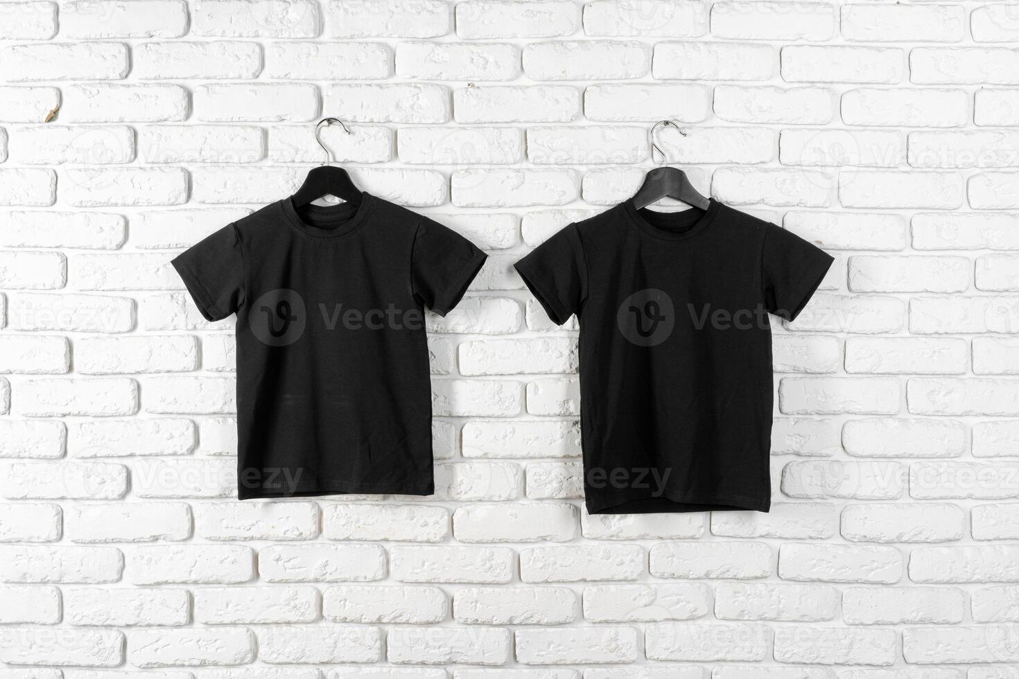 Black t-shirt hanging on a hanger against brick wall photo