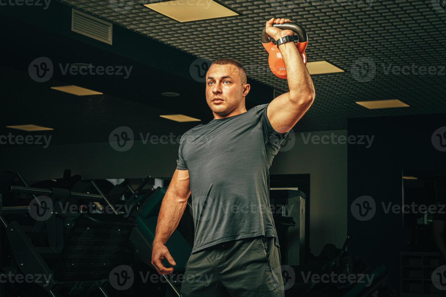 Bodybuilder doing exercises with dumbbells in a dark gym photo