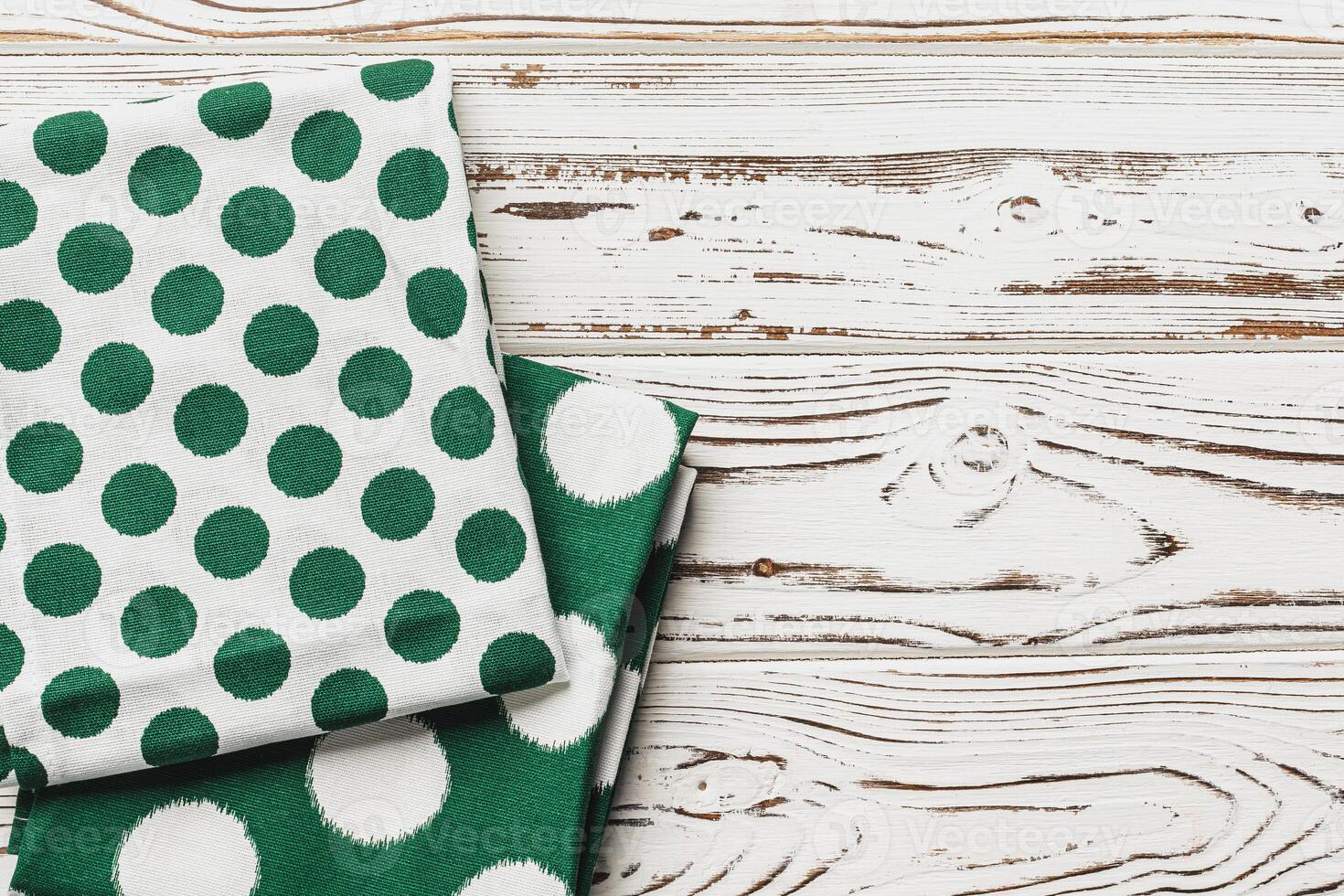 Green polka dot napkin on weathered wooden background photo