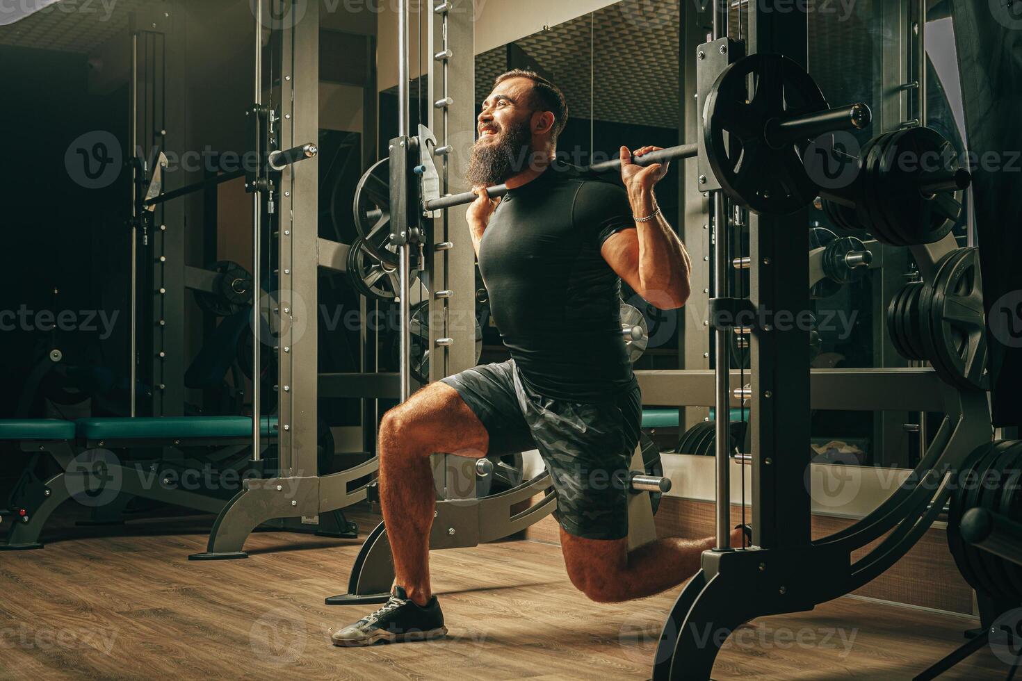 Fit man doing squats in a training machine photo