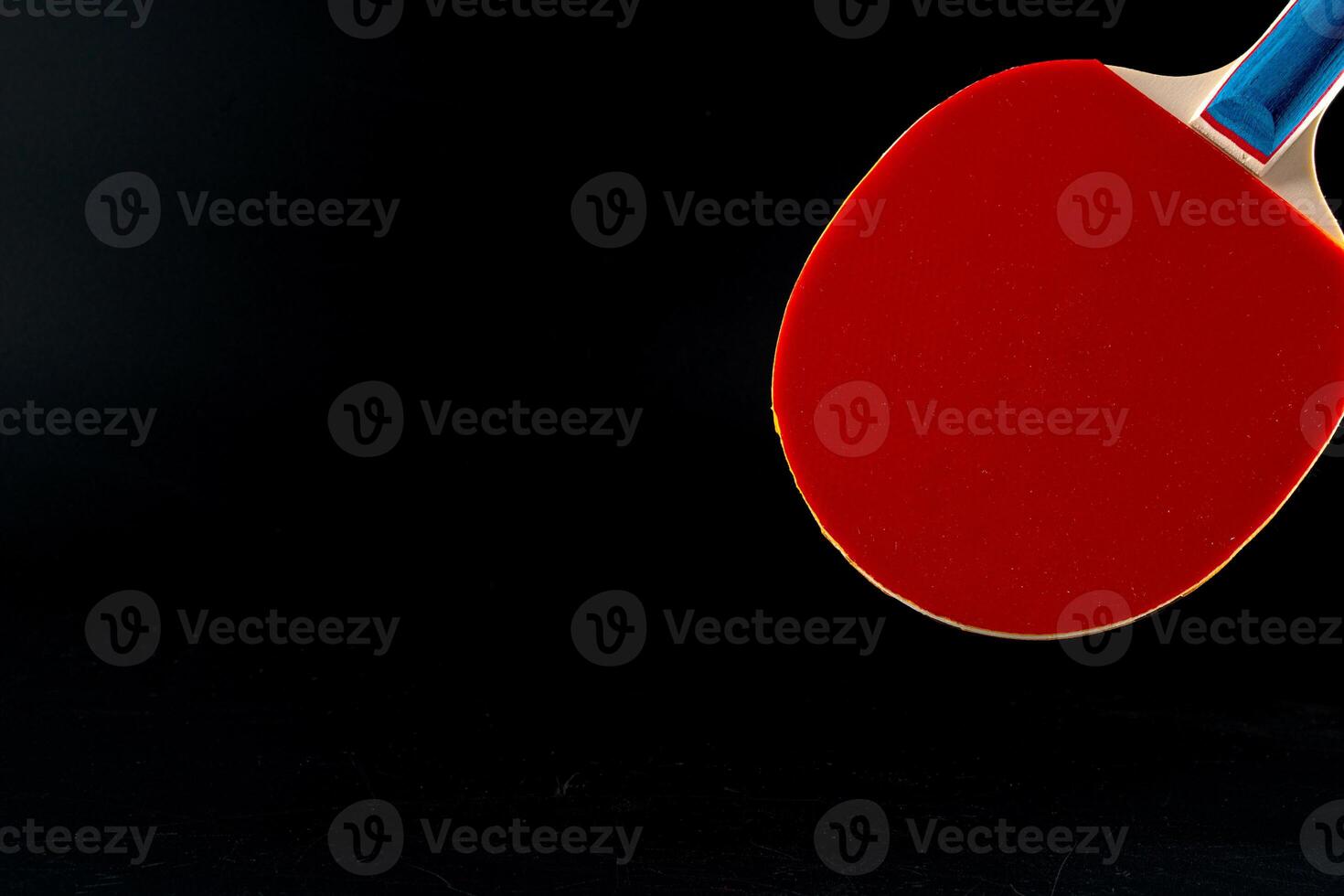 Red ping pong racket on dark background photo