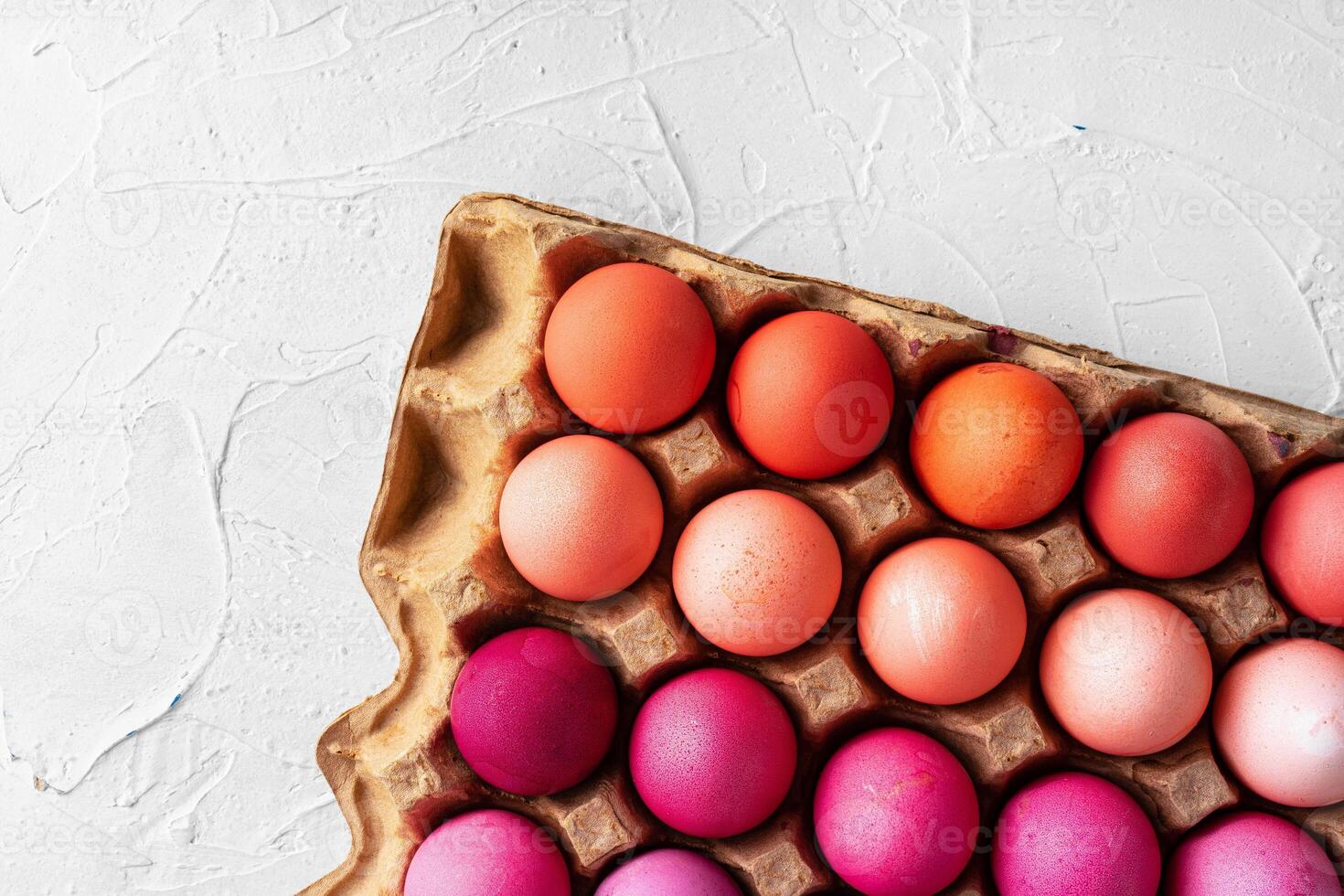 Several Easter eggs in different shades of pink in eggbox photo