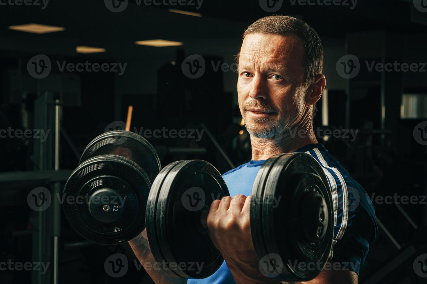 Senior man in his fifties lifting weights in a gym photo