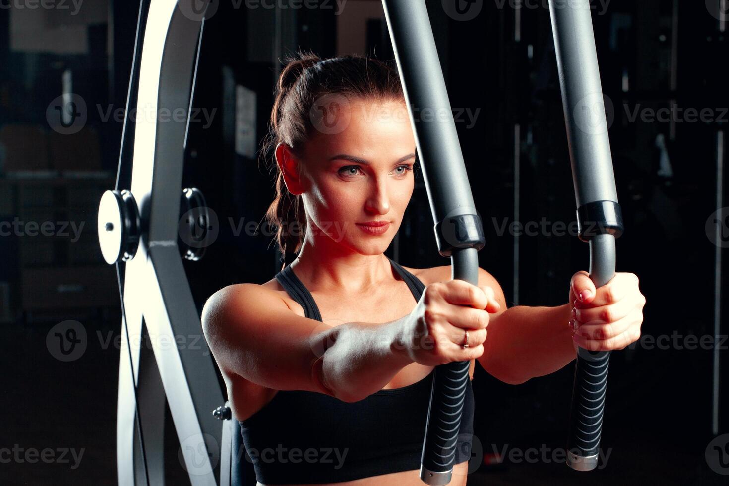 Young attractive woman doing exercises for arms in a training machine photo